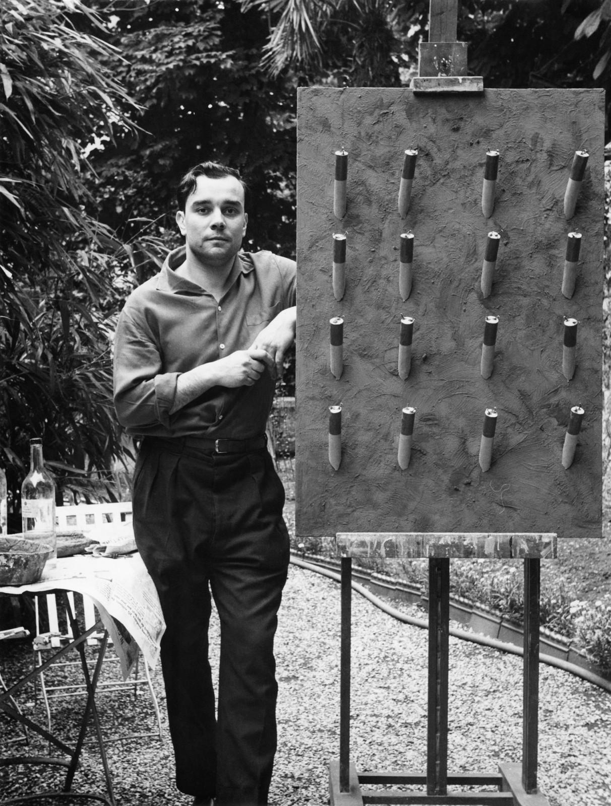 Yves Klein à côté du "Tableau de Feu bleu d'une minute" (M 41) présenté lors de l'exposition "Yves Klein : Propositions monochromes" à la Galerie Colette Allendy