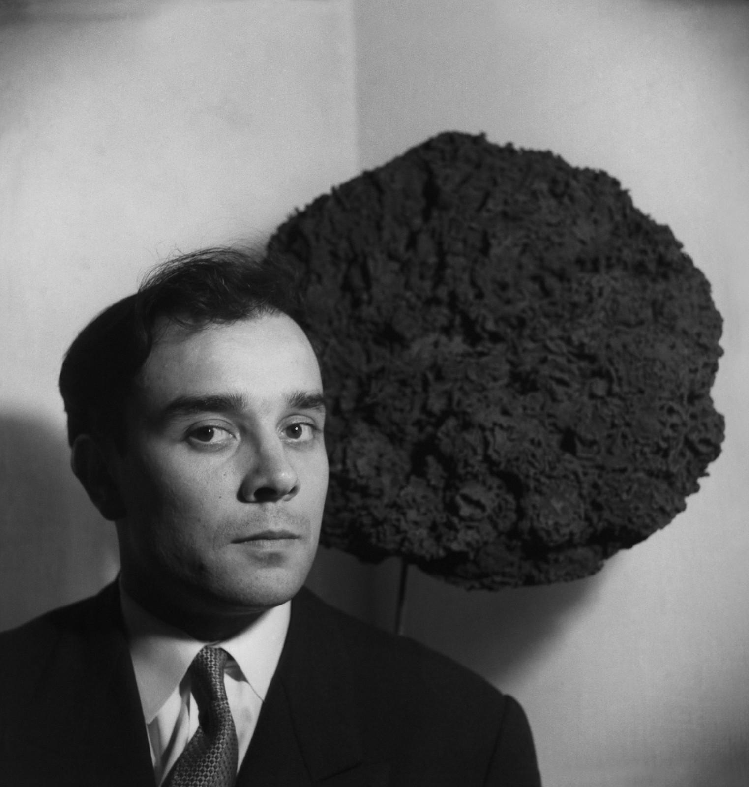 Yves Klein in front of his Sponge Sculpture at the exhibition "Monochrome Propositions of Yves Klein" Gallery One, London